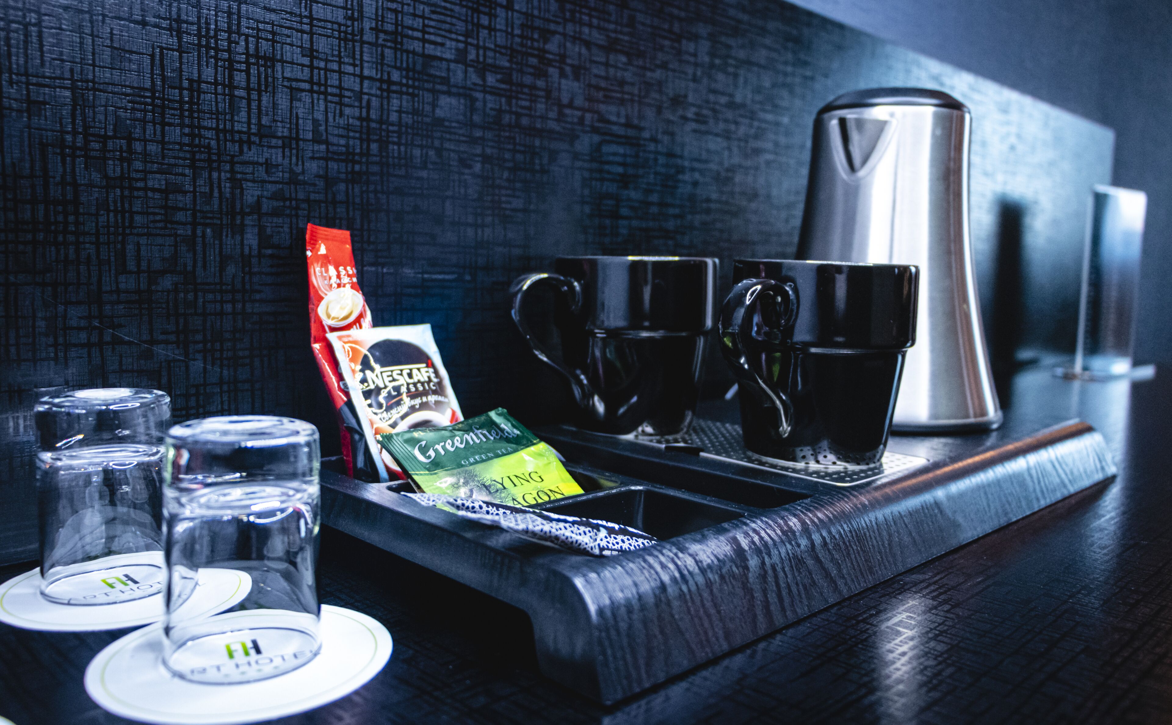 En kaffestation med en kaffebryggare, koppar och tepåsar.