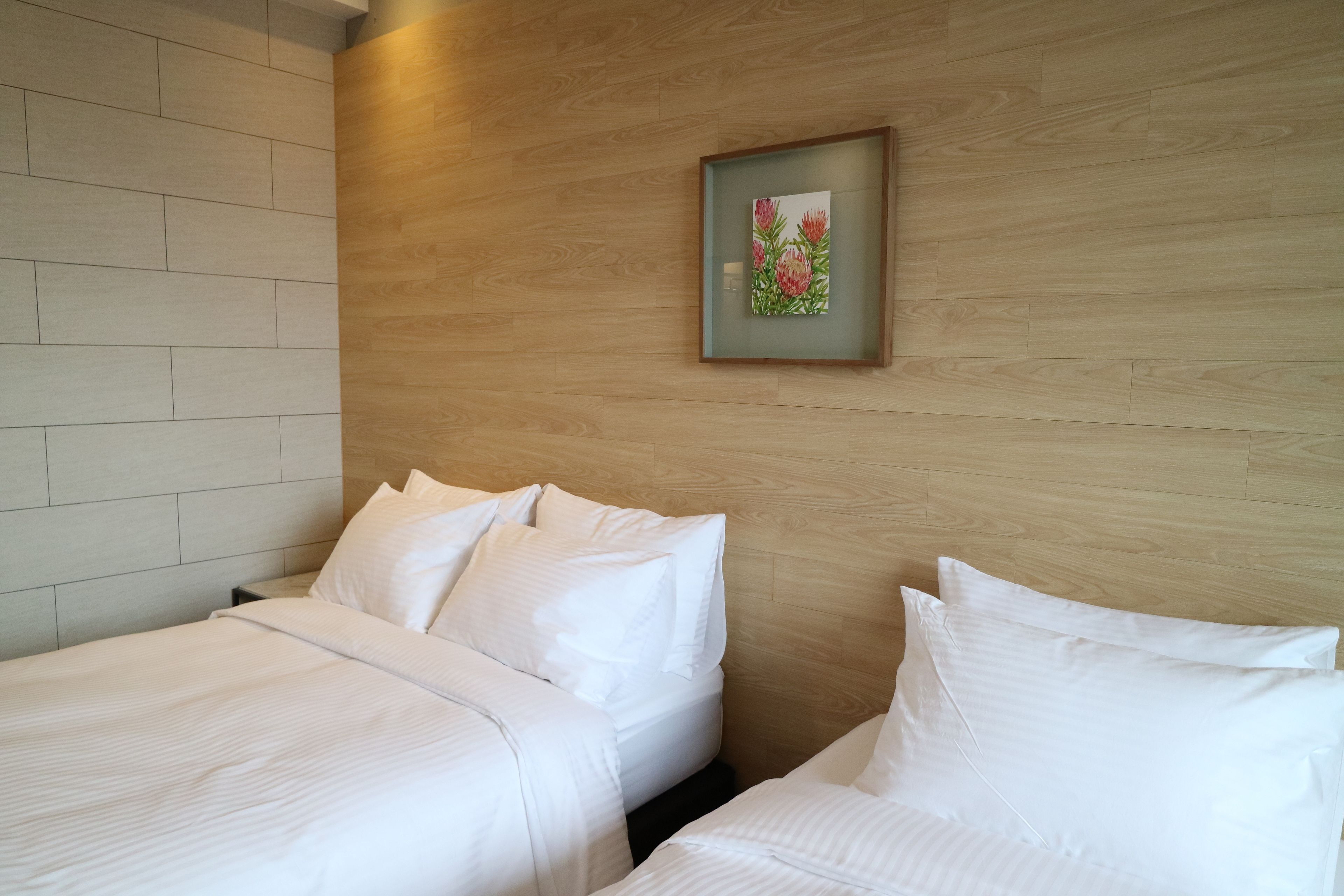 A hotel room with two beds, a wooden headboard, and a framed picture on the wall.