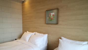 Una habitación de hotel con dos camas, cabecera de madera y un cuadro en la pared.