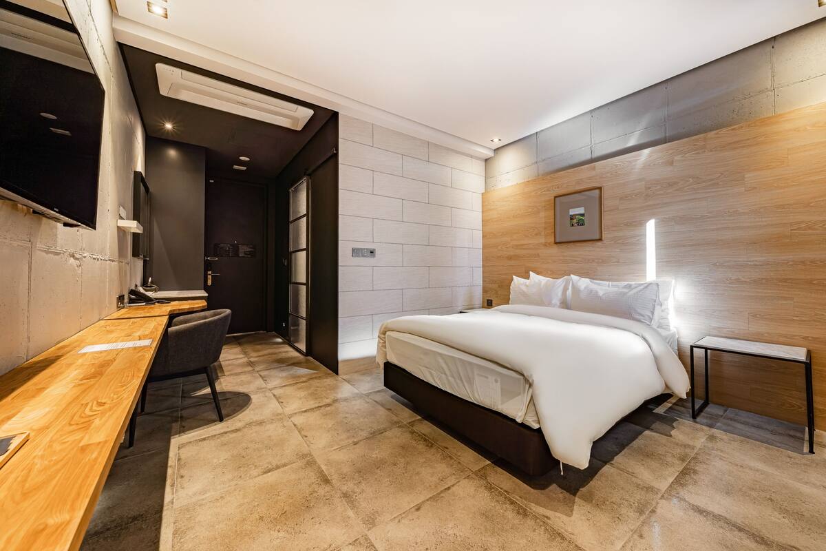 Une chambre d’hôtel moderne, dotée d’un grand lit, d’un bureau et d’une télévision.