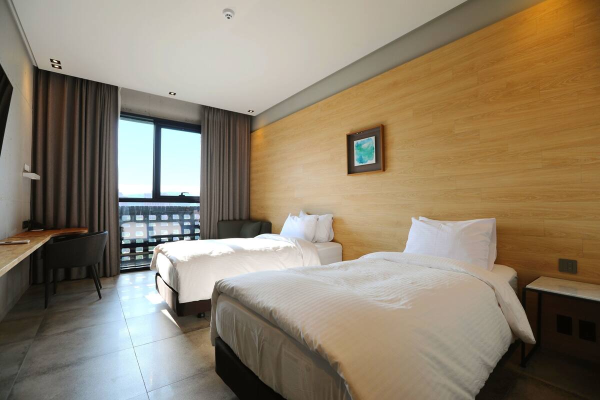 Une chambre d’hôtel avec deux lits, un bureau et une chaise.