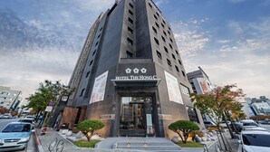 A tall hotel with a modern design, featuring a prominent entrance and a clear sky in the background. - The HongC Hotel Gangneung (Gangneung)