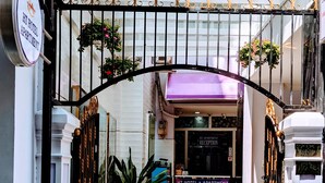A hotel entrance with a gated archway, a reception desk, and potted plants. - HT Hotel Apartment (Ho Chi Minh City)