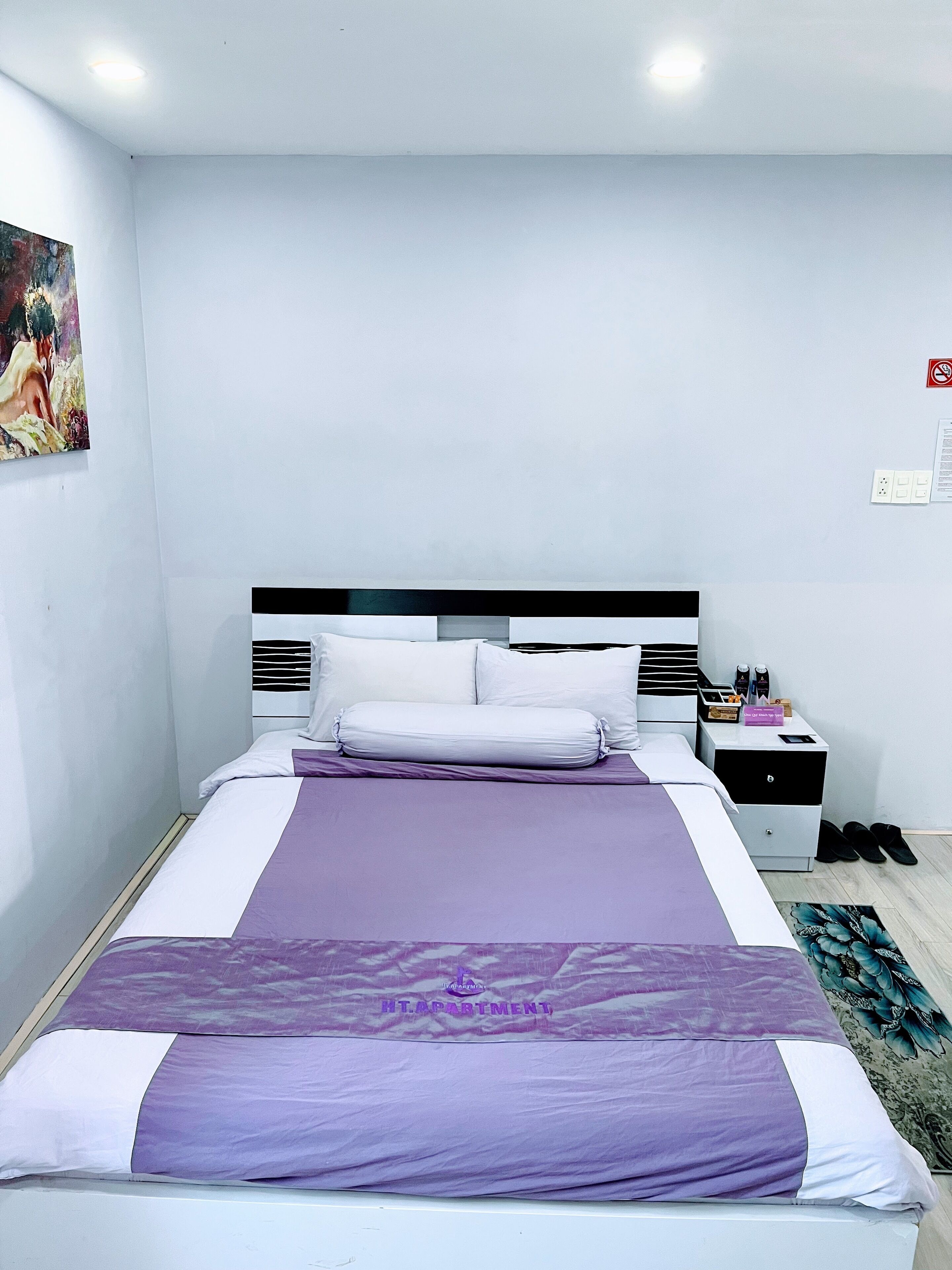 A neatly arranged bedroom with a bed, a nightstand, and a wall-mounted light fixture.