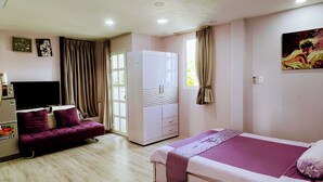 A bedroom with a bed, a sofa, a wardrobe, a television, and a window. - HT Hotel Apartment (Ho Chi Minh City)