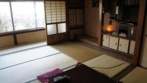 A tatami mat room with a futon bed, a remote control, and a traditional Japanese lantern. - Miyoshiya Ryokan (Tanabe)