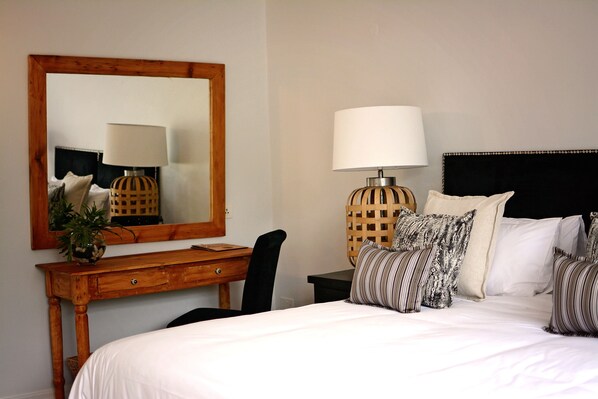 A neatly arranged bedroom with a large bed, a wooden desk, a chair, a lamp, and a mirror. - Number Eighteen Exclusive Guest Lodge (Harare)