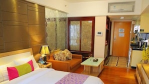 A hotel room with a bed, a sofa, a small table, and a kitchenette. - YUMI Apartment-Pujun Station Branch (Foshan)