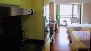 A hotel room with a kitchenette, two beds, a desk, and a window with curtains. - YUMI Apartment-Pujun Station Branch (Foshan)