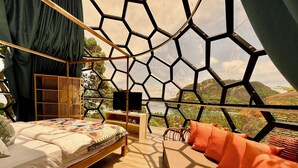 A bedroom with a bed, a TV, and a view of a mountainous landscape.