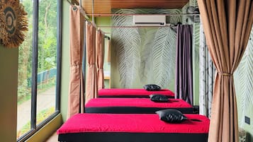 Ein Zimmer mit drei Betten, großen Fenstern und Blick auf Grünfläche.