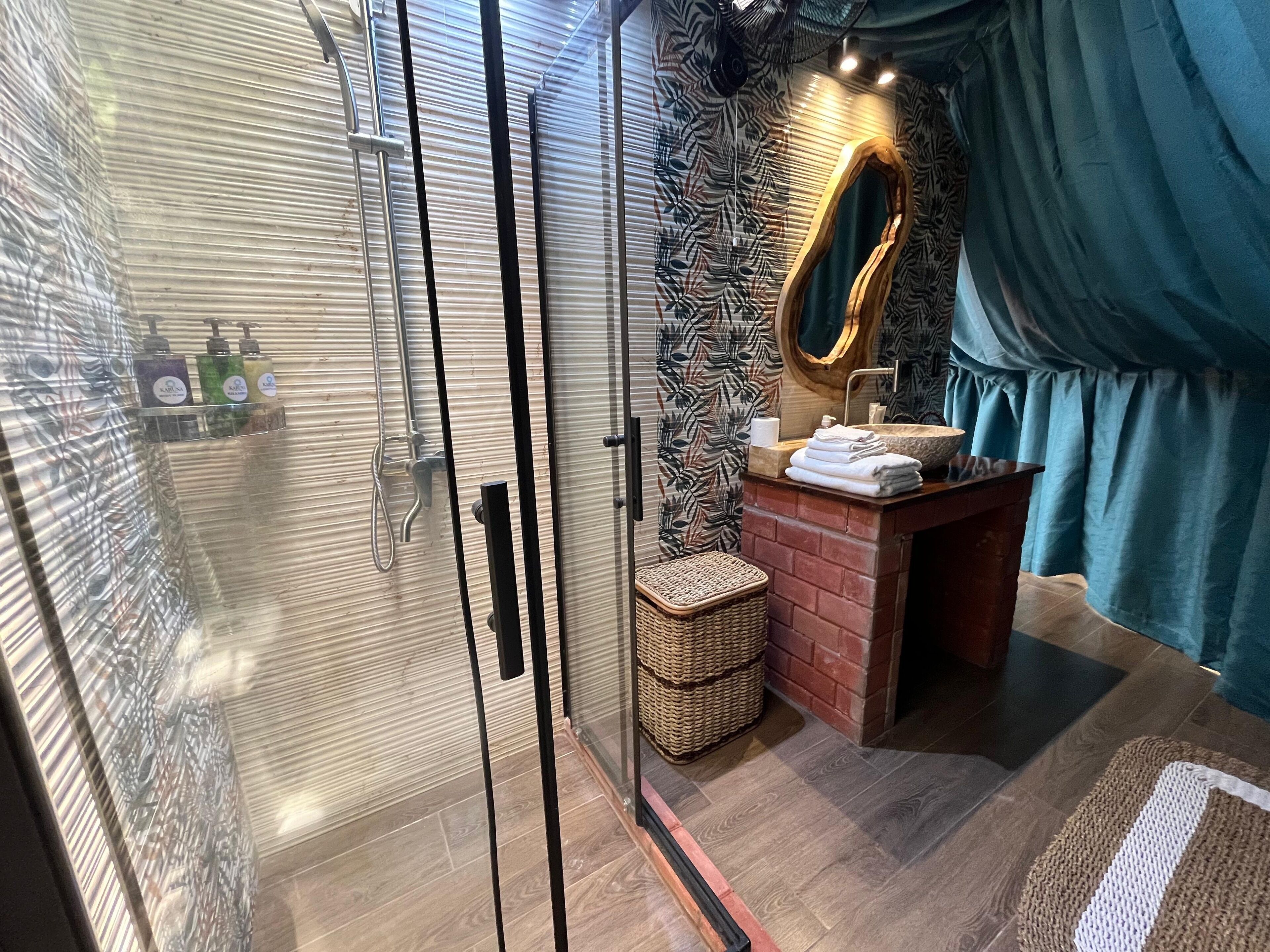 A bathroom with a glass-enclosed shower, a wooden vanity with a sink, and a mirror.