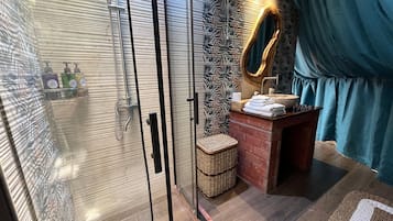A bathroom with a glass-enclosed shower, a wooden vanity with a sink, and a mirror.
