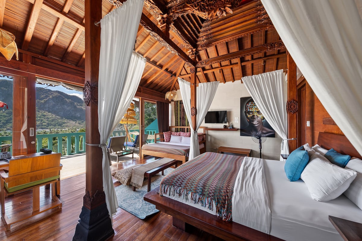 Een ruime slaapkamer met een groot bed, een houten bureau en uitzicht op de bergen.
