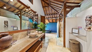 A bathroom with a wooden bench, a large stone basin, and a mirror.