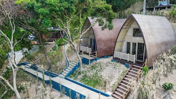 Two dome-shaped cabins with external staircases, surrounded by trees and vegetation.
