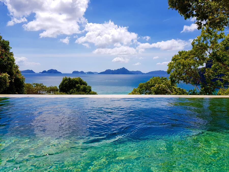 A clear view of a swimming pool with a view of the sea and distant islands.