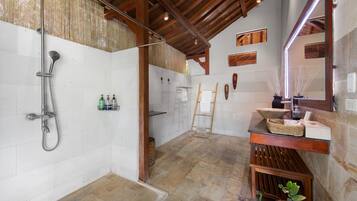 Une salle de bain spacieuse avec une douche, un banc en bois, un lavabo avec un miroir et un porte-serviettes.
