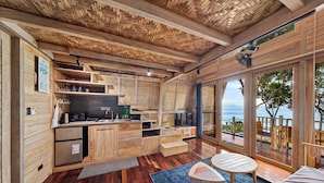 A wooden interior with a kitchen, dining area, and large windows overlooking a scenic view.