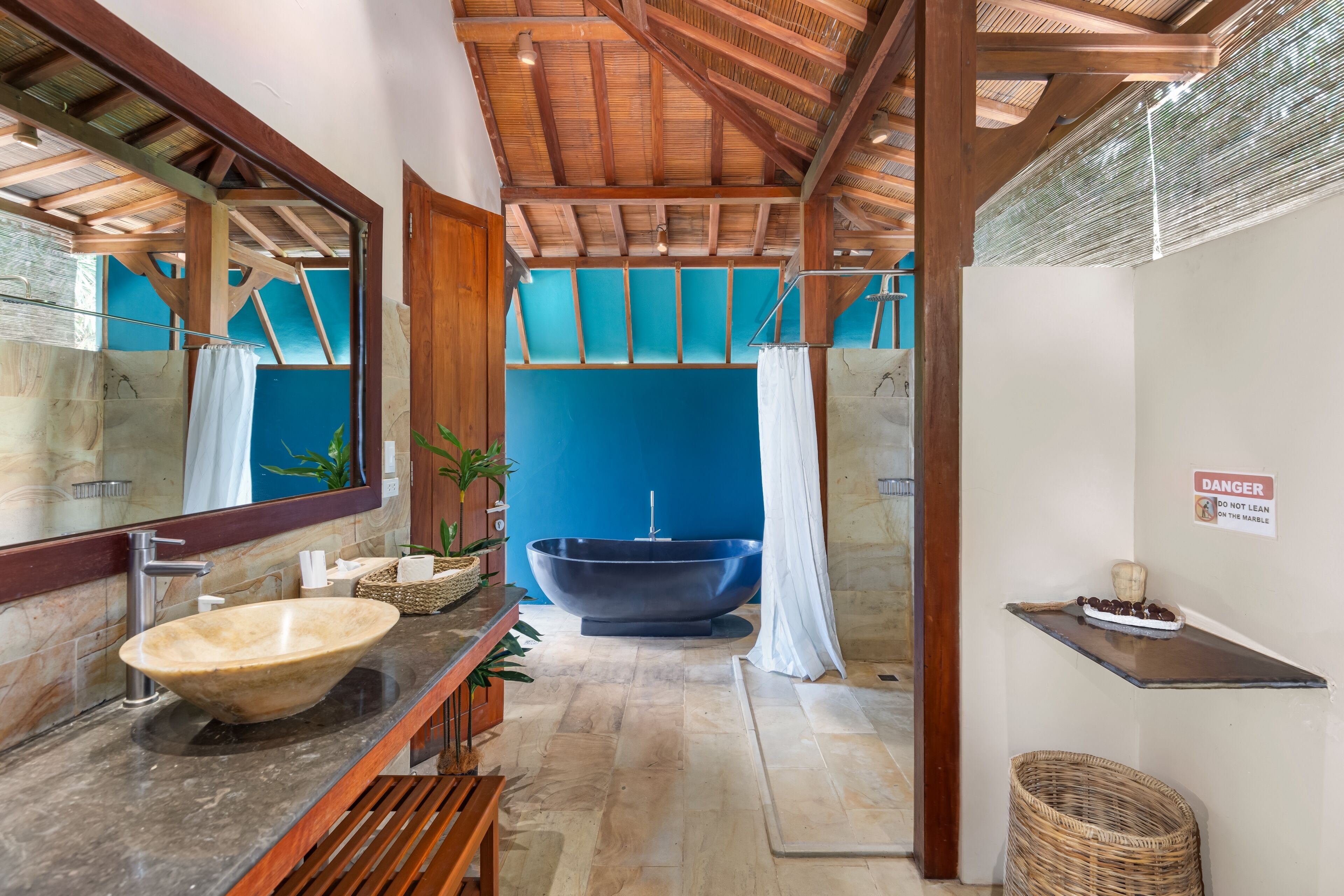 A modern bathroom with a large freestanding bathtub, a marble sink, and a wooden ceiling.