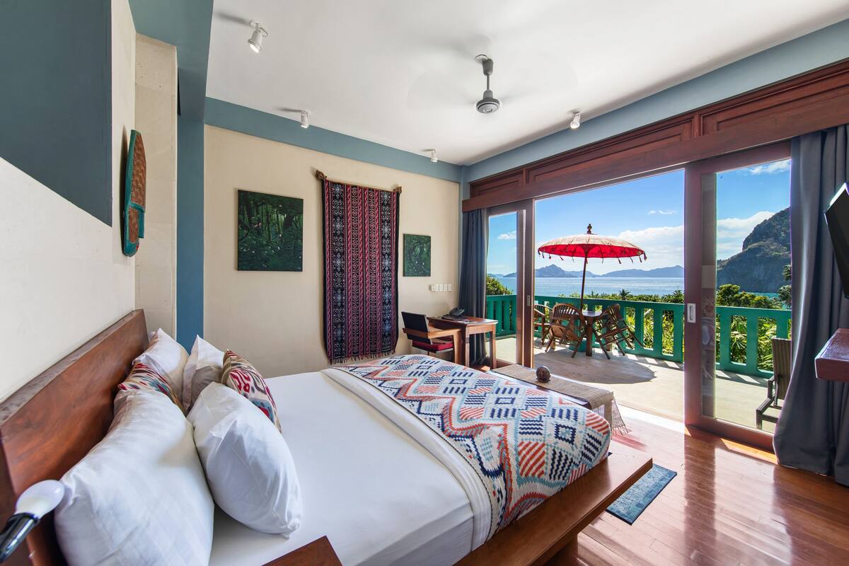 Een slaapkamer met een bed, een bureau en uitzicht op de oceaan.