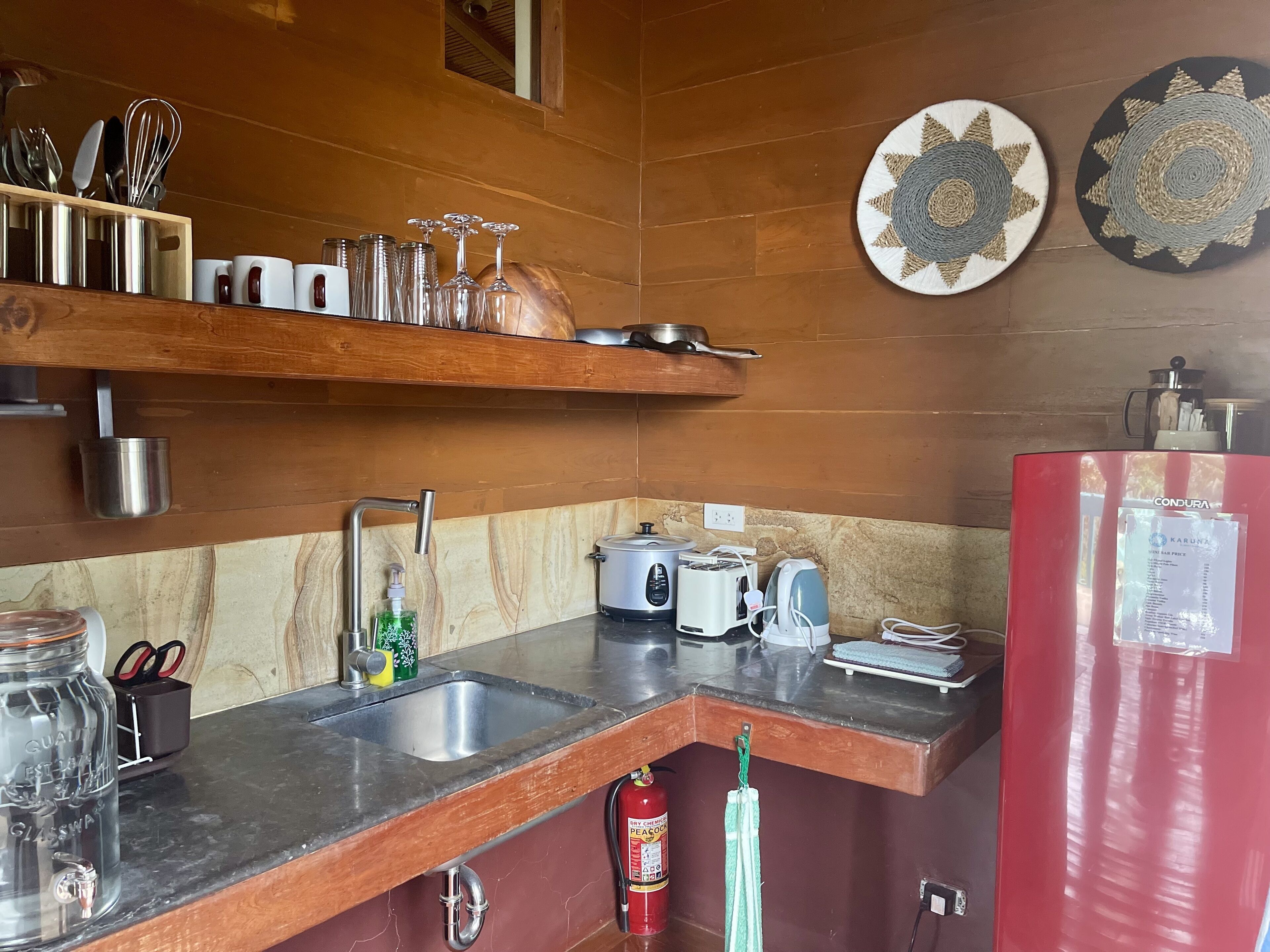 A compact kitchen with a sink, a toaster, a kettle, and a red refrigerator.
