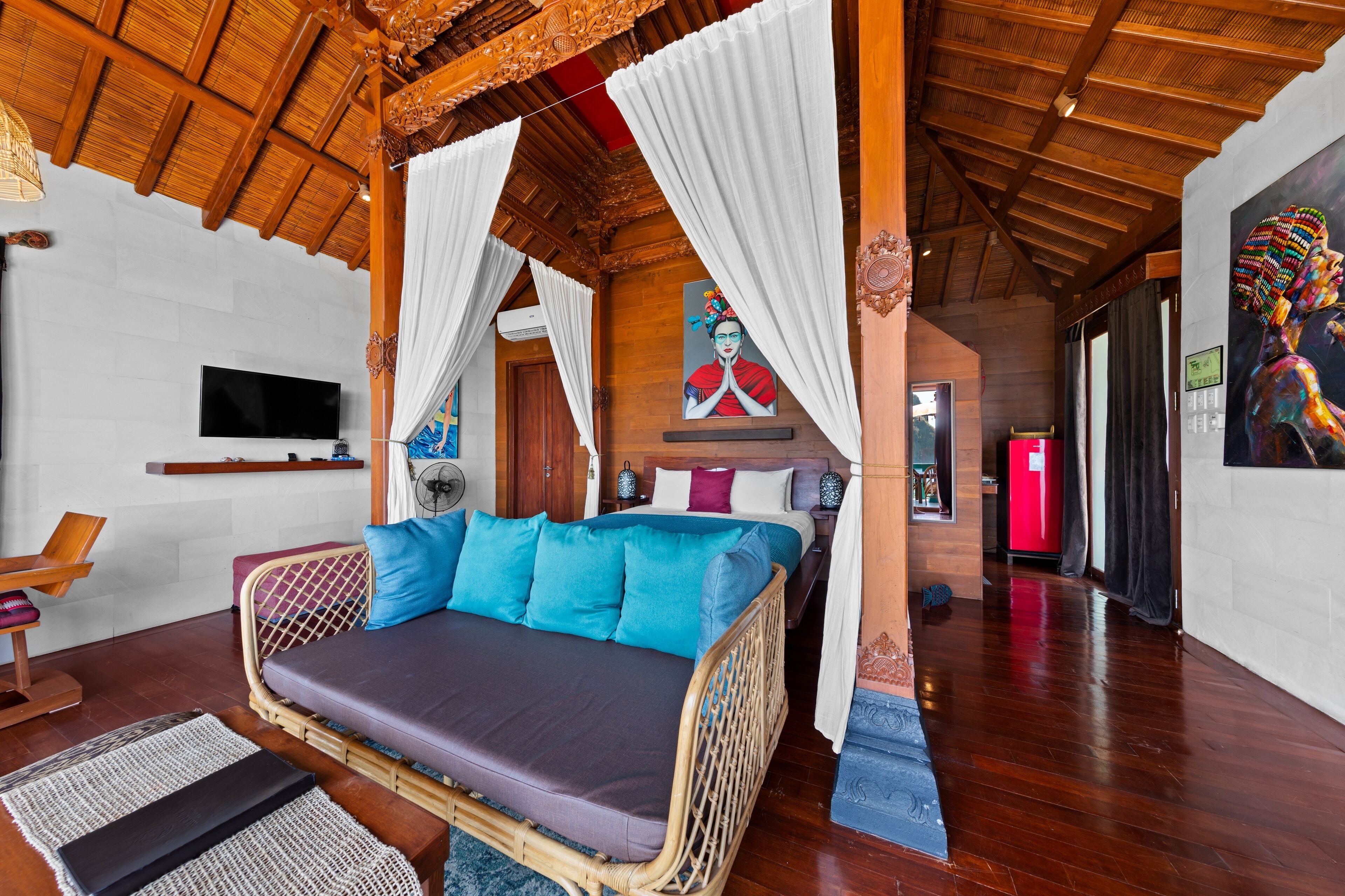 A room with a bed, a TV, and a painting on the wall.