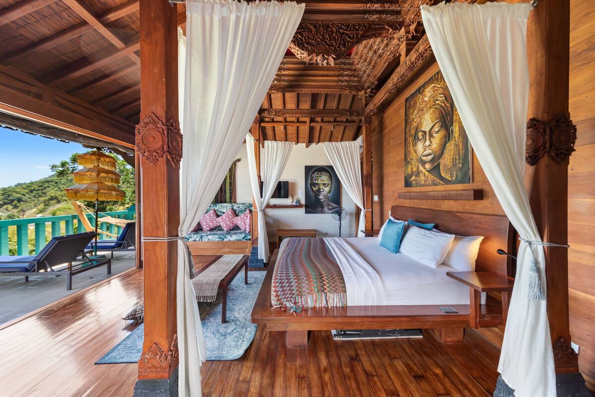 Een houten kamer met een bed, gordijnen en een schilderij.