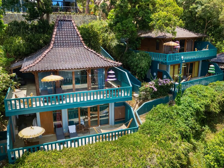 A two-story building with a traditional tiled roof, a balcony with a railing, and a covered seating area.