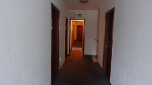 A narrow hallway with carpeted floors and wooden doors on either side. - Hotel-Restaurant Dümptener Hof (Muelheim an der Ruhr)