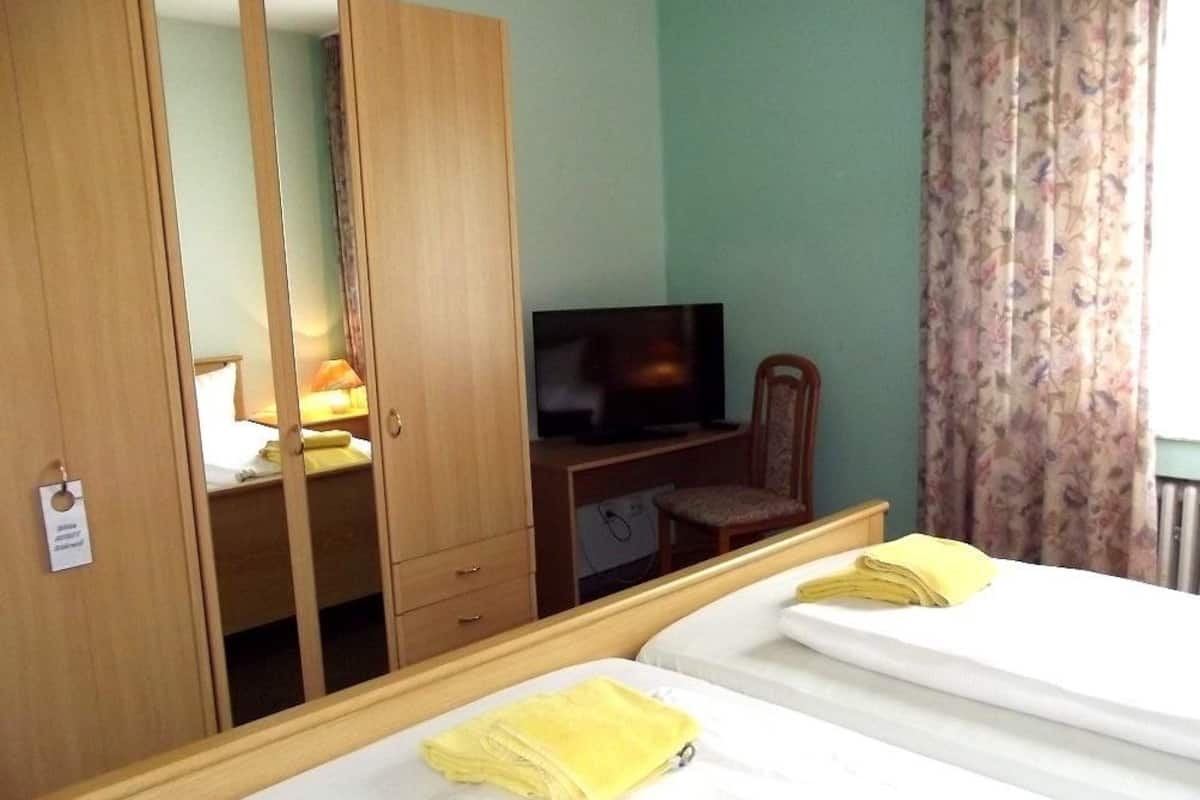 A hotel room with two beds, a TV, a desk, and a wardrobe.