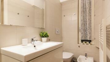 A modern bathroom with a large mirror, a sink, a toilet, and a bidet.