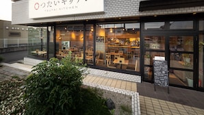 Un restaurant amb un cartell que diu "TSUTAI KITCHEN" i un quadre de taules amb el menú a l'exterior.