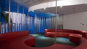 A modern interior with a curved red seating area, a tall column structure, and a blue accent wall. - Mood - Private Suites (Montijo)
