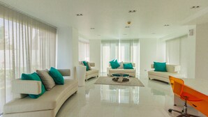 A spacious living room with white sofas, teal cushions, and a bright, glossy floor. - City Center Residence by PSR ASIA (Pattaya)