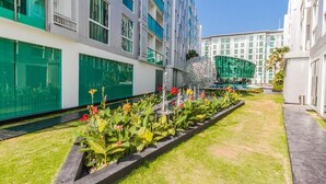 A modern hotel with a garden area featuring a water fountain and various plants. - City Center Residence by PSR ASIA (Pattaya)