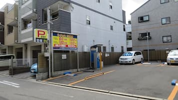 A parking lot with a sign indicating a 24-hour parking rate of 100 yen per hour.