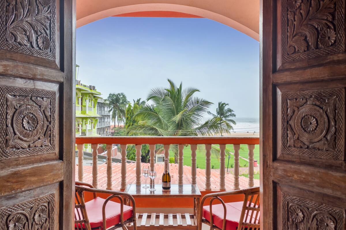 A balcony with a table, two chairs, and a bottle of champagne.