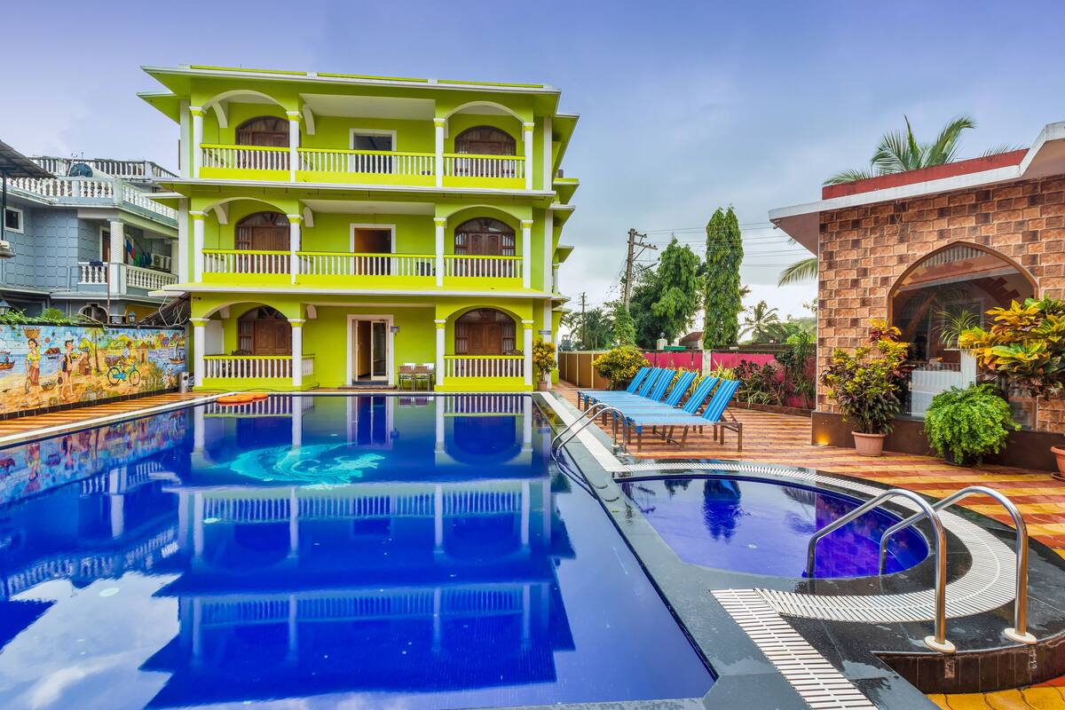 A two-story building with a swimming pool, outdoor seating, and a brick structure with a window.