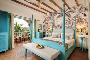 Un dormitorio con cama con dosel, un banco con fruta y un papel tapiz tropical.