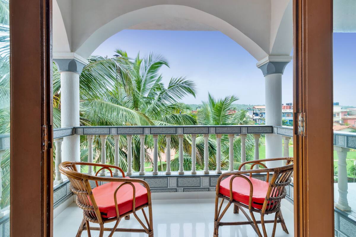 A balcony with two wicker chairs and a white balustrade.