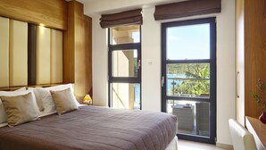 Ein Schlafzimmer mit einem großen Bett, einer Balkontür und Blick ins Freie.
