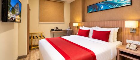 A hotel room with a large bed, a desk, a chair, a television, a painting, and a telephone.