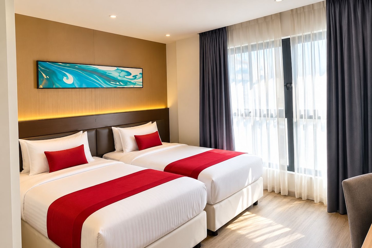 Een hotelkamer met twee bedden, een groot raam met gordijnen en een schilderij aan de muur.