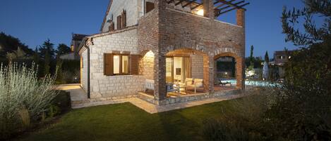 A stone house with a covered patio and a swimming pool.