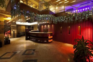 A hotel lobby with a reception desk, a staircase, and a red wall. - White Orchid (Cox's Bazar)