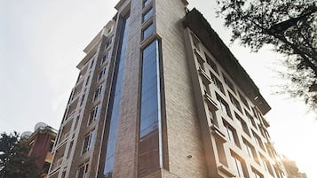 Un edificio de varios pisos con un diseño arquitectónico moderno, destacando una fachada de vidrio vertical y una serie de balcones.