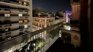 Vista noturna de uma varanda com vista para uma paisagem urbana, com edifícios modernos e históricos.