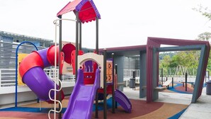 A playground with a purple slide, red and purple climbing structures, and a covered play area. - Duet HomeStay (Seri Kembangan)