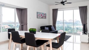 A modern living room with a dining table, black chairs, a black sofa, a ceiling fan, and large windows with curtains. - Duet HomeStay (Seri Kembangan)